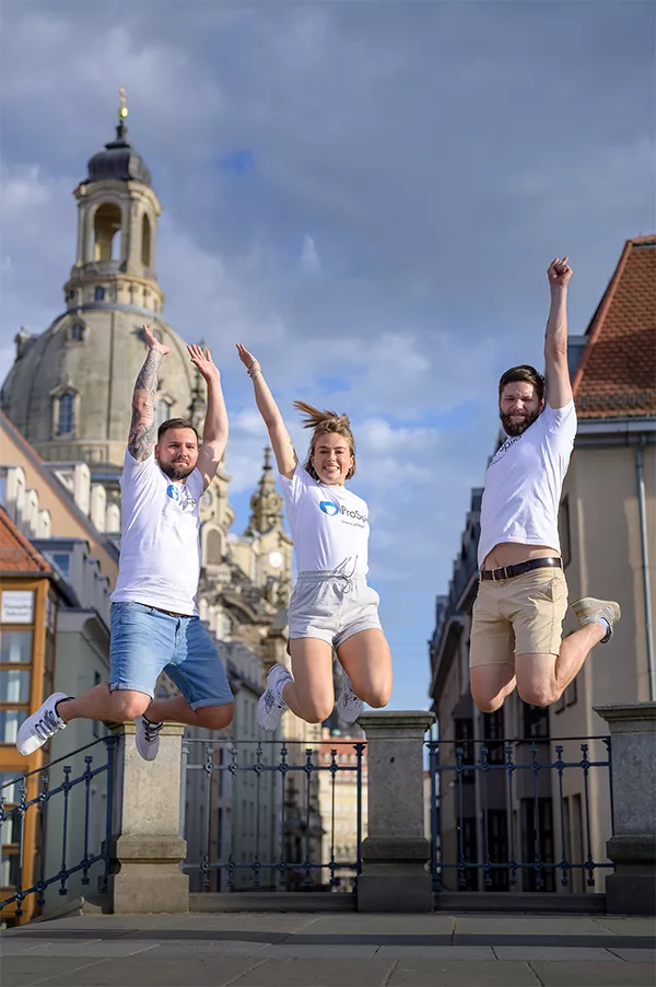 3 Pflegefachkräfte vom Intensivpflege-Dienst ProSpiro springen in die Luft vor der Frauenkirche Dresden