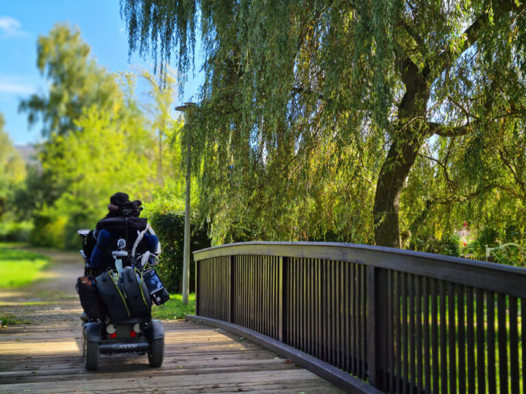 Patient in Zwickau fährt mit dem Rollstuhl auf einer Brücke im Park