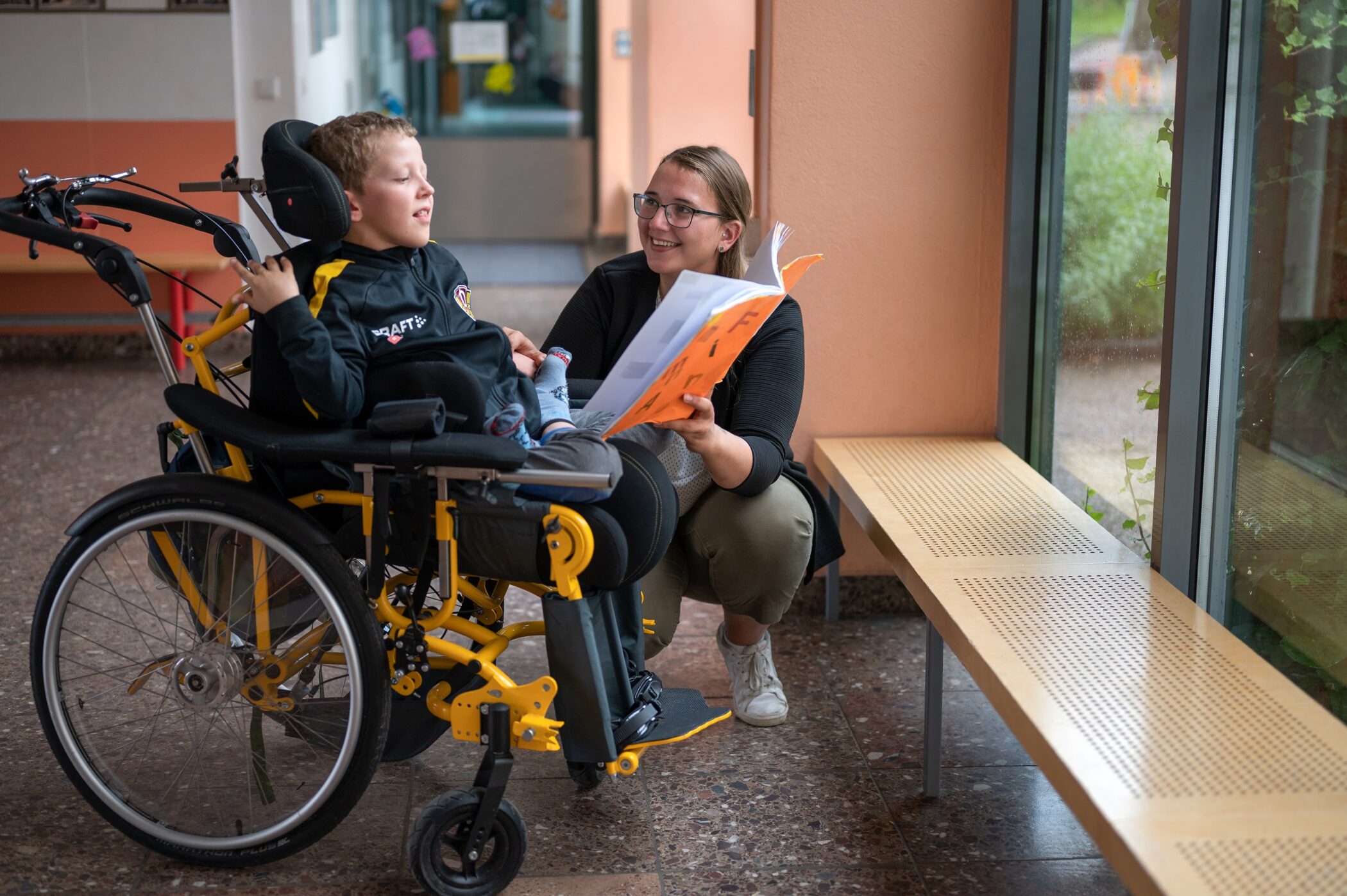 Pflegefachkraf tmit Kind im Rollstuhl in der Schule